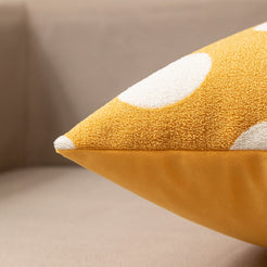 Loop-pile textured polyester pillow cover with raised white polka dots on mustard yellow, shown in a side view on a sofa