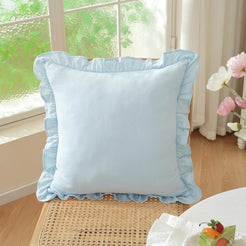 Light blue solid cotton pillow cover with ruffled edges on a chair