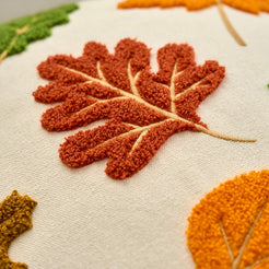 Close-up of dense raised embroidery on embroidered polyester canvas pillow cover with a rust oak leaf