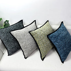 Chenille-textured polyester pillow covers with gray, olive and blue covers with black trim, on a white sofa