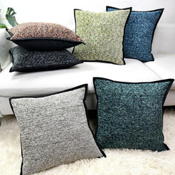 Chenille-textured polyester pillow covers with assorted chenille colors with black edged trim, grouped on a white sofa