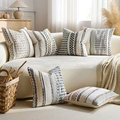 Chenille-textured polyester pillow covers with mixed neutral striped designs, grouped on a cream sofa