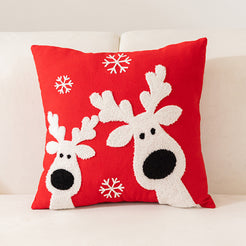 embroidered polyester canvas pillow cover with white reindeer and snowflakes on red, shown on a cream sofa