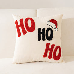 embroidered polyester canvas pillow cover with HO HO HO lettering and Santa hat on cream, shown on a cream sofa