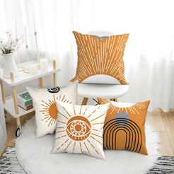short-pile plush polyester pillow covers with orange sunburst and arch designs, arranged beside a white chair