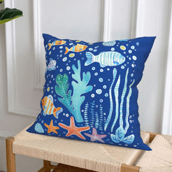short-pile plush polyester pillow cover with colorful fish, coral and starfish on blue, styled on a woven chair