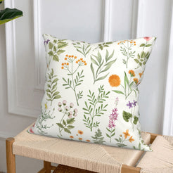 short-pile plush polyester pillow cover with delicate green herbs and colorful wildflowers, styled on a woven chair