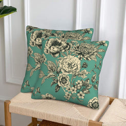Set of two velvet pillow covers with green dense rose and chrysanthemum print, styled on a woven chair