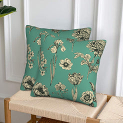 Set of two green velvet pillow covers with mixed floral stems, styled on a woven chair