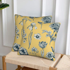 Set of two velvet pillow covers with mustard yellow mixed floral stems, styled on a woven chair