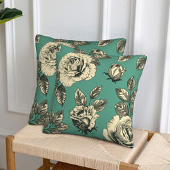 Set of two velvet pillow covers with green rose print, styled on a woven chair