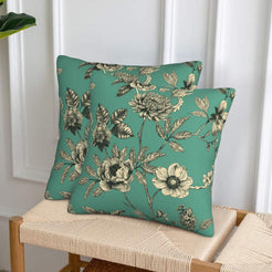 Set of two velvet pillow covers with green mixed floral stems, styled on a woven chair