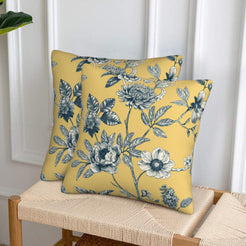 Set of two velvet pillow covers with mustard yellow floral branches, styled on a woven chair