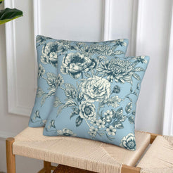 Set of two velvet pillow covers with light blue and navy large florals, styled on a woven chair