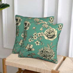 Set of two green velvet pillow covers with roses and chrysanthemums, styled on a woven chair