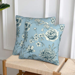 Set of two velvet pillow covers with light blue rose spray, styled on a woven chair