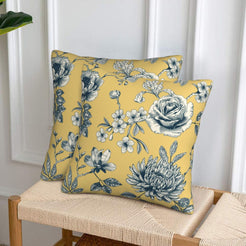 Set of two velvet pillow covers with mustard yellow dense rose and chrysanthemum print, styled on a woven chair