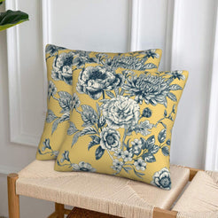 Set of two velvet pillow covers with mustard yellow and blue large florals, styled on a woven chair