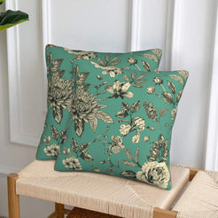 Set of two green velvet pillow covers with chrysanthemums and mixed flowers, styled on a woven chair