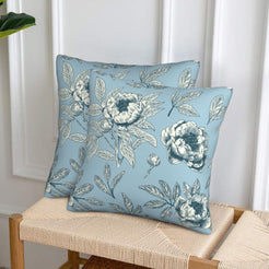 Set of two velvet pillow covers with light blue peony print, styled on a woven chair