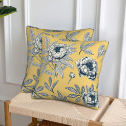 Set of two velvet pillow covers with mustard yellow peony print, styled on a woven chair