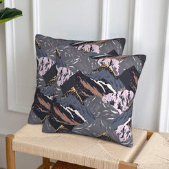 Set of two velvet pillow covers with charcoal and lilac mountains, styled on a woven chair