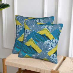 Set of two velvet pillow covers with teal and lime green mountains, styled on a woven chair