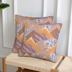 Set of two velvet pillow covers with taupe and orange mountains, styled on a woven chair