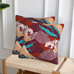 Set of two velvet pillow covers with burgundy mountains with aqua accents, styled on a woven chair