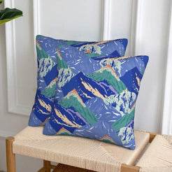 Set of two velvet pillow covers with blue and green mountains, styled on a woven chair