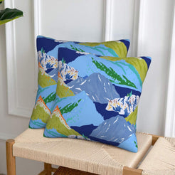 Set of two velvet pillow covers with blue and lime green mountains, styled on a woven chair