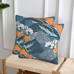 Set of two velvet pillow covers with teal mountains with orange accents, styled on a woven chair