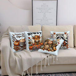 Four light blue fall pillow covers with Highland cow, pumpkin spice, harvest and raccoon designs, styled on a sofa