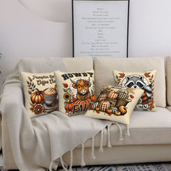 Four cream fall pillow covers with Highland cow, pumpkin spice, harvest and raccoon designs, styled on a sofa