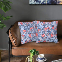 Velvet pillow covers with blue and red seashells and coral, styled on a sofa
