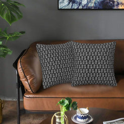 Velvet pillow covers with small gray block-print-inspired motifs, styled on a brown leather sofa