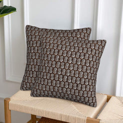 Velvet pillow covers with small brown block-print-inspired motifs, styled on a woven chair