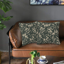 Bohemian velvet pillow covers with cream botanical silhouettes on dark green, styled on a brown leather sofa