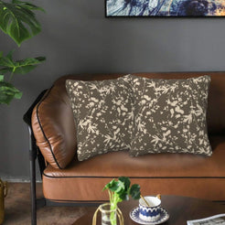 Bohemian velvet pillow covers with cream botanical silhouettes on taupe, styled on a brown leather sofa