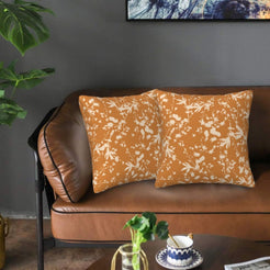 Bohemian velvet pillow covers with cream botanical silhouettes on burnt orange, styled on a brown leather sofa