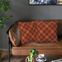 Fall velvet pillow covers with orange and brown diagonal plaid, styled on a brown leather sofa
