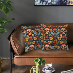 Mexican-inspired velvet pillow covers with sugar skulls and flowers on dark teal, styled on a brown leather sofa