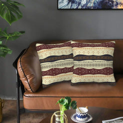 Velvet pillow covers with cream, burgundy and black horizontal bands, styled on a leather sofa