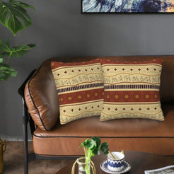 Velvet pillow covers with tan and rust cross-and-stripe bands, styled on a leather sofa