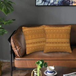 Velvet pillow covers with ochre tonal geometric bands, styled on a leather sofa