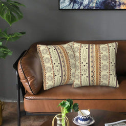 Velvet pillow covers with cream vertical mask and symbol motifs, styled on a leather sofa