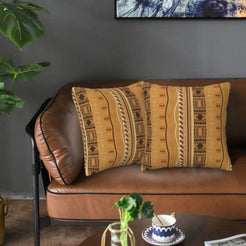 Velvet pillow covers with tan and black vertical geometric stripes, styled on a leather sofa