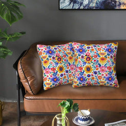 Mexican-inspired velvet pillow covers with bright multicolor flowers on white, styled on a brown leather sofa