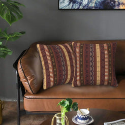 Velvet pillow covers with burgundy, purple and tan vertical bands, styled on a leather sofa