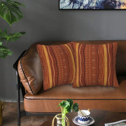 Velvet pillow covers with terracotta vertical geometric stripes, styled on a leather sofa